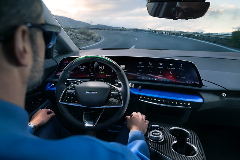Front View of the 2026 OPTIQ-V Driving Through the Dusk Utilizing its Headlights | Harvey Cadillac in Grand Rapids MI