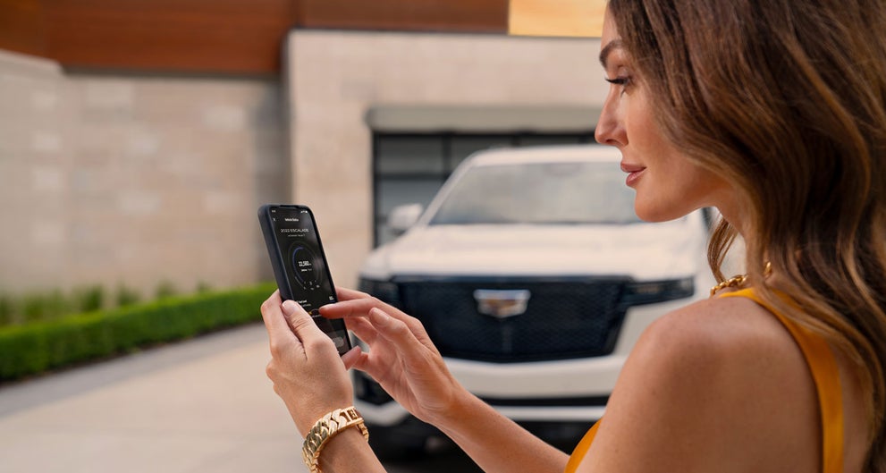 lady checking her mobile with a Cadillac vehicle background | Harvey Cadillac in Grand Rapids MI